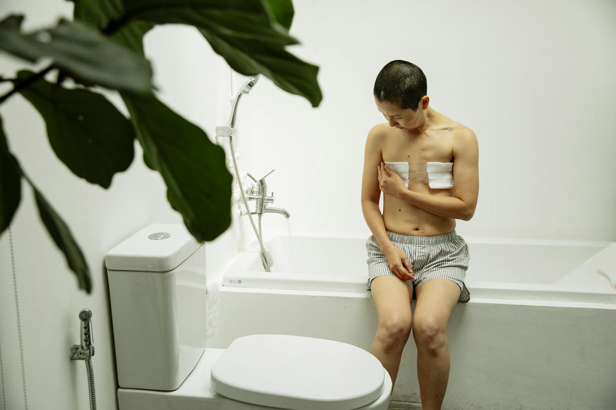Asian woman with short hair in bathroom recovering from surgery, showing resilience and hope.