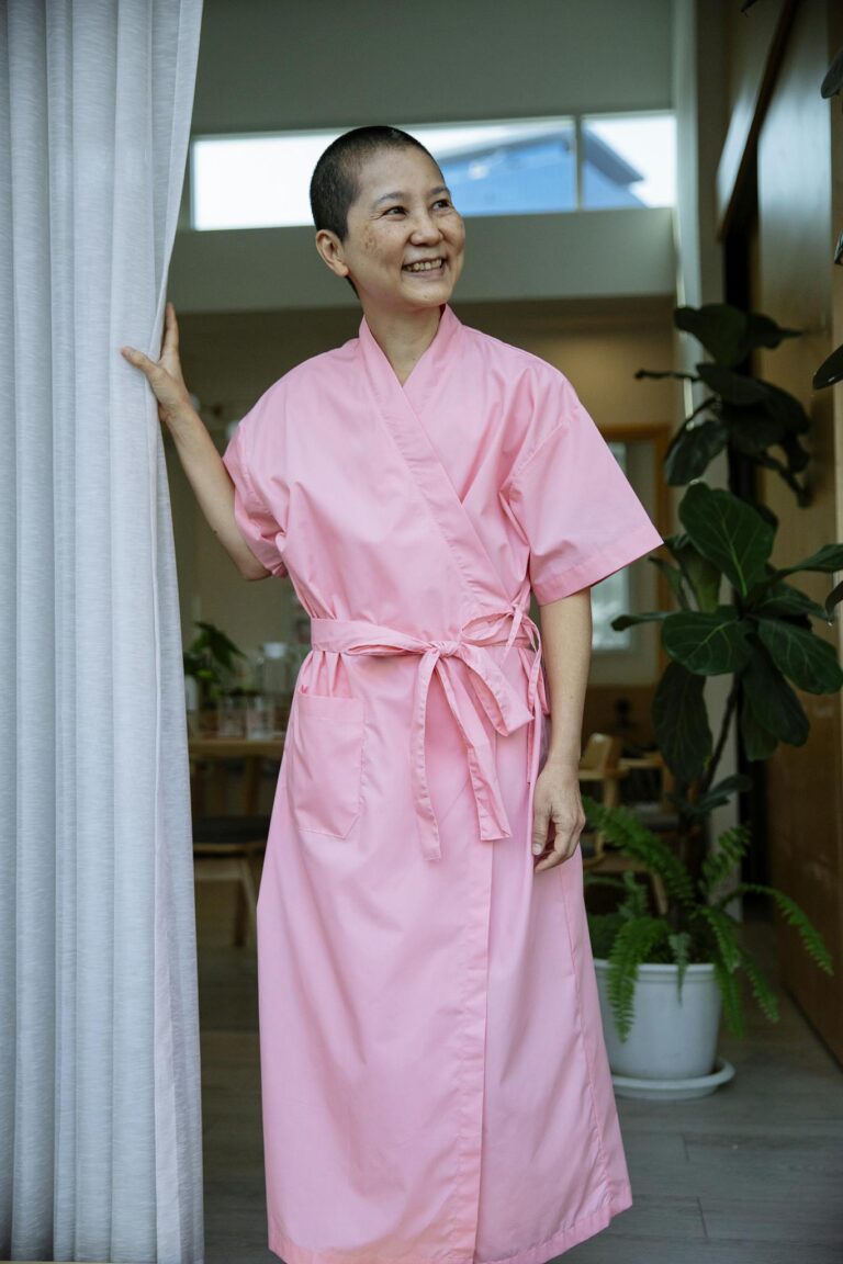 Happy ethnic female suffering from breast cancer smiling and looking away on rehabilitation in hospital